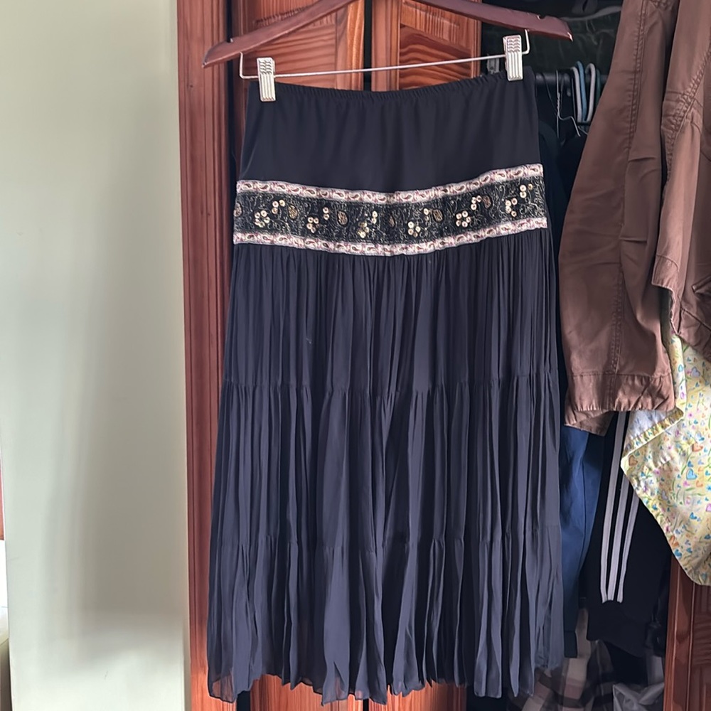 Skirt. Pleated. Black with slip under. Has a strip of gold festive sequins.